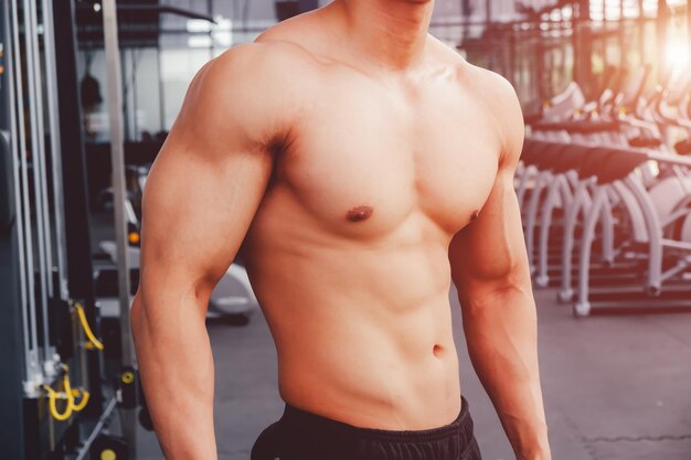 Foto sezione centrale di un uomo senza camicia in piedi in palestra