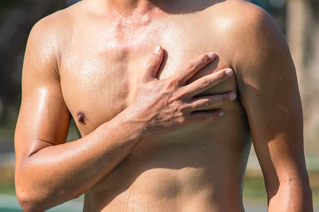 Foto sezione centrale di un uomo senza camicia che tocca il petto nel dolore