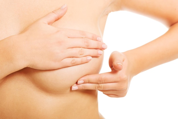 Midsection of shirtless woman touching breast against white background