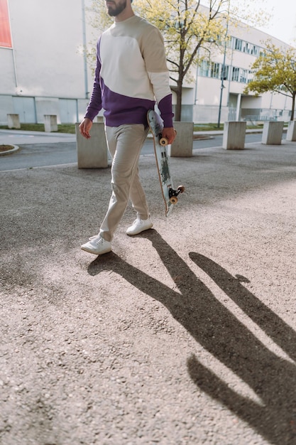 Midsection of skateboarder Stylish cool man walking down the street Urban spot Vertical photo High quality photo