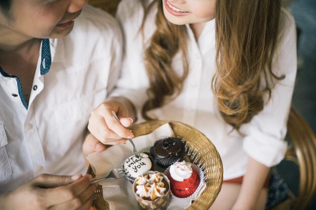 Foto sezione centrale di una coppia sorridente che mangia il dessert in un caffè