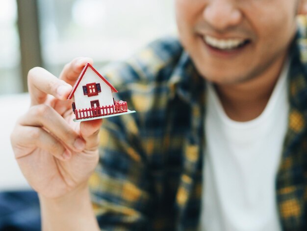 Foto sezione centrale di un uomo sorridente che tiene una casa modello a casa