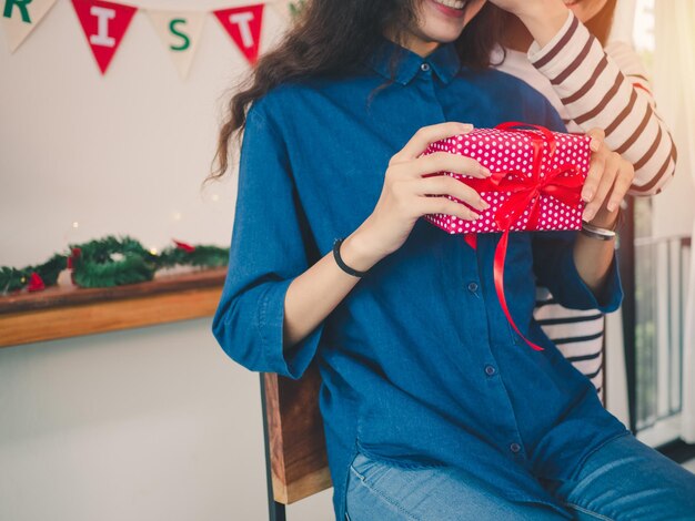 Photo midsection of smiling woman holding christmas present by friend at home