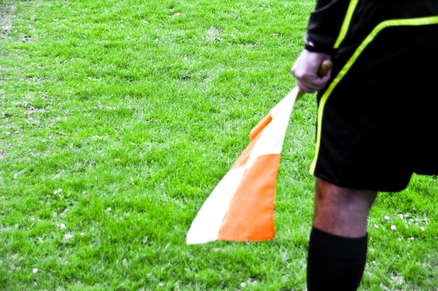 Foto sezione centrale di uno sportivo con una bandiera su un campo erboso