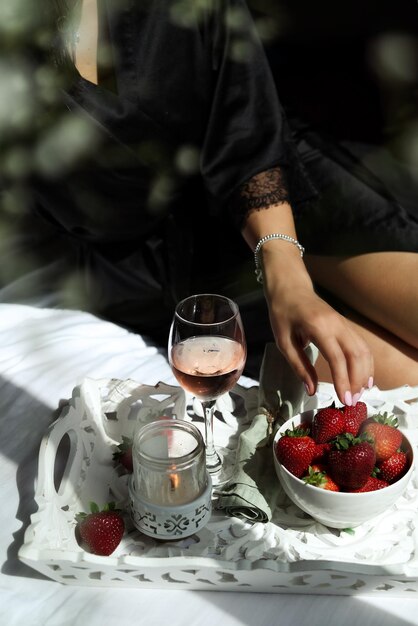 Foto sezione centrale di fragola che tiene il gelato sul tavolo con un bicchiere di vino rosato