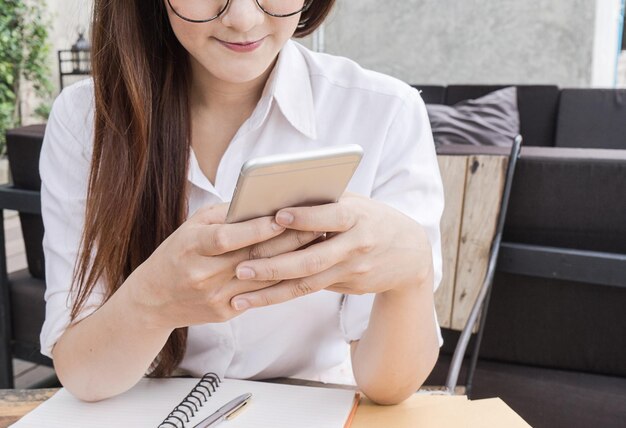 Midsection of student using mobile phone at desk