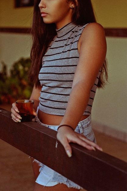 Photo midsection of teenage girl holding drink while standing by wood