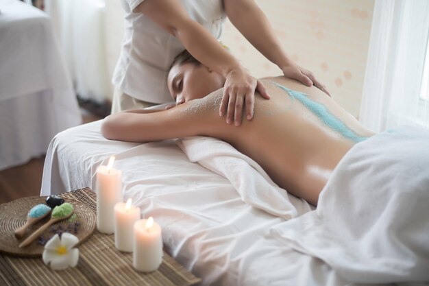 Foto sezione centrale di un terapeuta che massaggia una giovane donna in una spa.