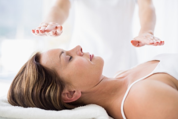 Midsection of therapist performing reiki treatment on woman