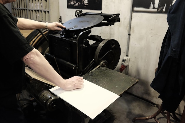 Foto sezione centrale di un tipografo che utilizza macchinari durante il lavoro in officina