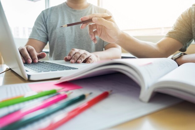 Photo midsection of university students using laptop at table