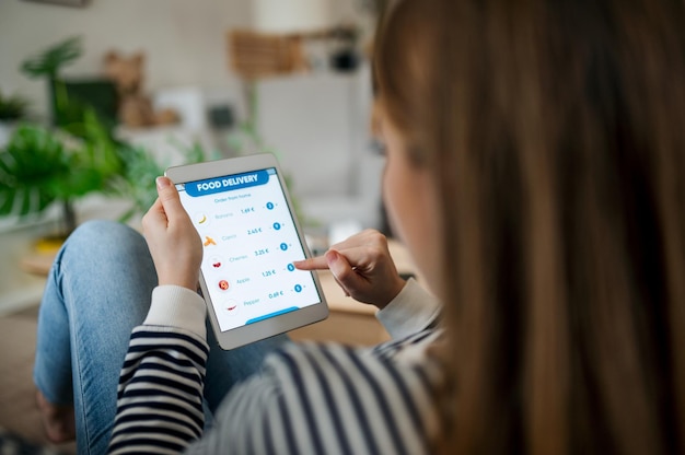 Midsection of unrecognizable woman with tablet ordering food at home