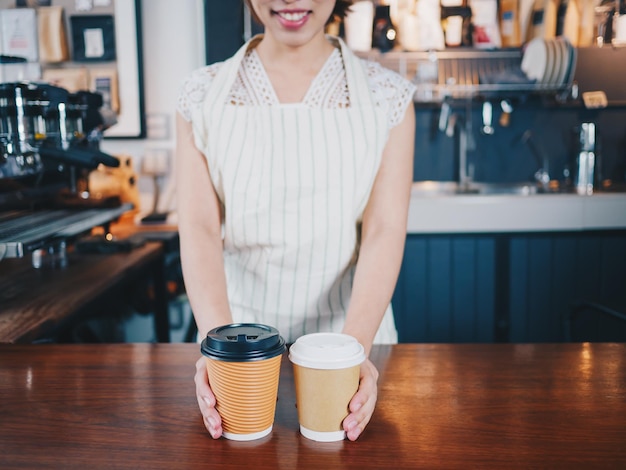 Midsection van vrouw die wegwerpbekers vasthoudt terwijl ze in een café staat