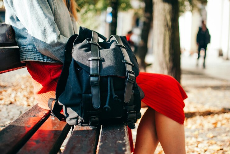 Foto midsection van vrouw met rugzak die op een bankje in het park zit