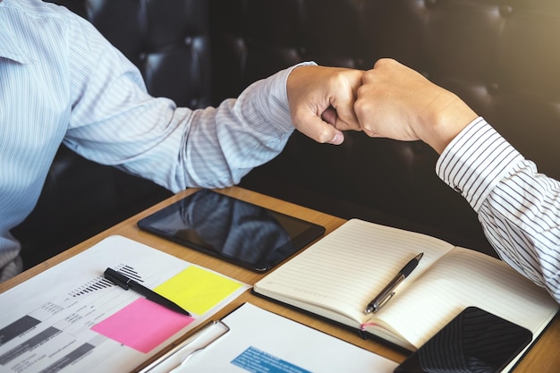 Midsection van zakenman die vuist slaat met collega door kantoorbenodigdheden op het bureau