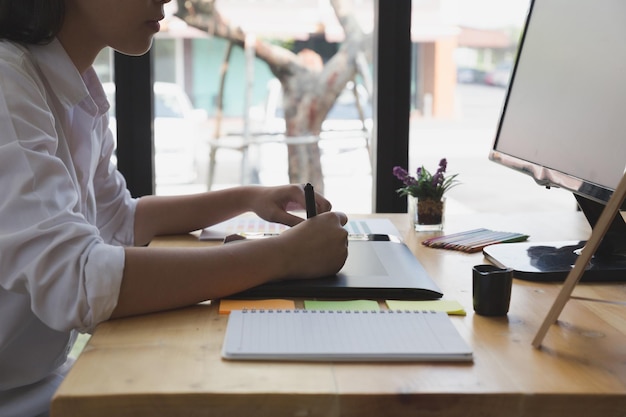 Midsection van zakenvrouw met grafische tablet met gedigitaliseerde pen door computer op tafel