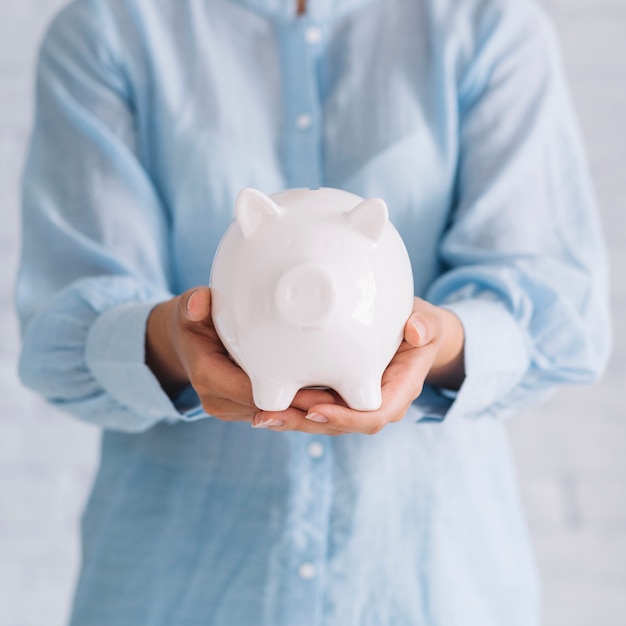 Photo midsection view of a woman's hand holding white piggybank