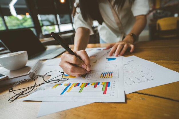 Photo midsection of woman analyzing charts by laptop on table in cafe