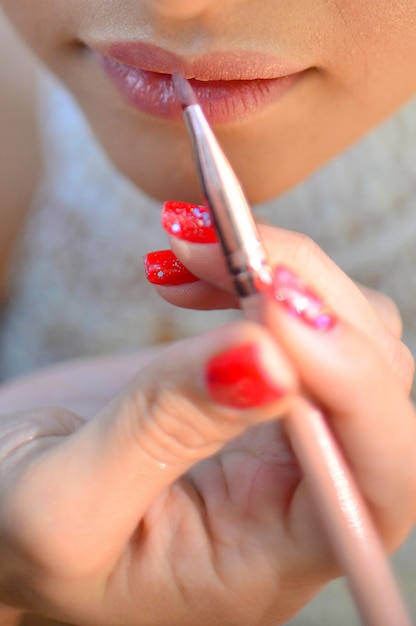 Midsection of woman applying lipstick