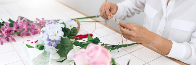 Foto sezione centrale di una donna che dispone un bouquet di fiori sul tavolo