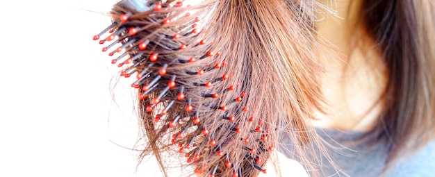 Foto sezione centrale di una donna che si spazzola i capelli su uno sfondo bianco