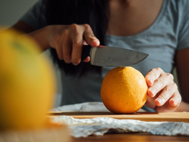 Photo midsection of woman cutting orange on board