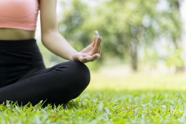 midsection of woman doing yoga while sitting at field