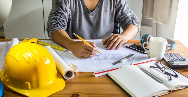 midsection of woman drawing blueprint in office