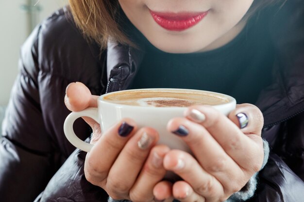 カップでコーヒーを飲んでいる女性の中央部分