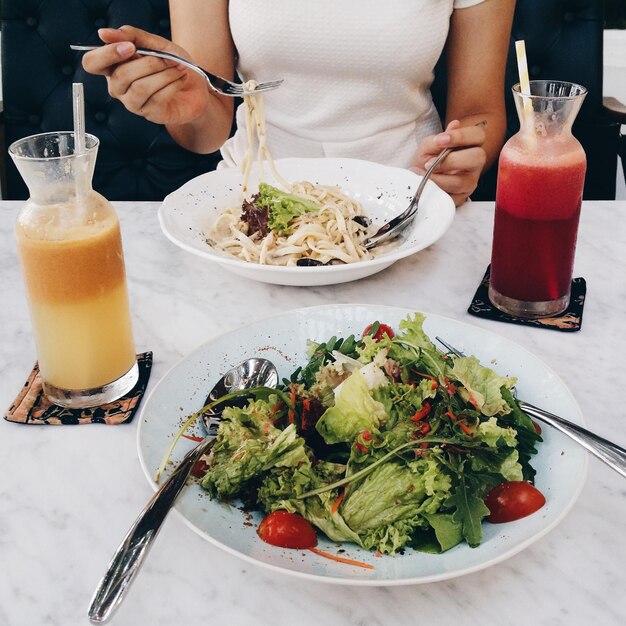 Midsection of woman eating noodles at restaurant