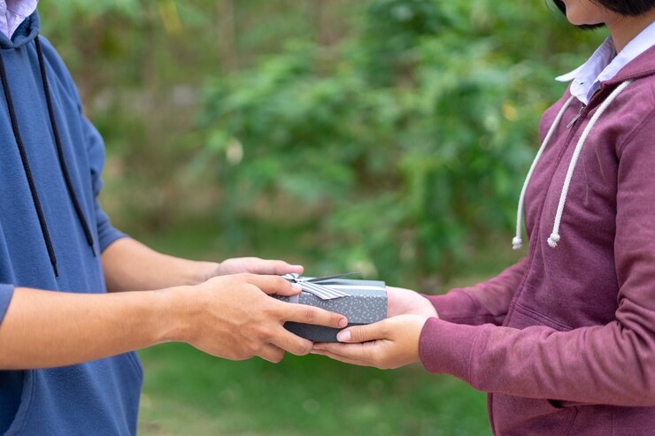 Photo midsection of woman gifting man while standing outdoors
