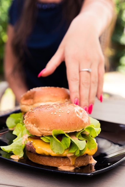 Foto sezione centrale di una donna che mangia un hamburger sul piatto
