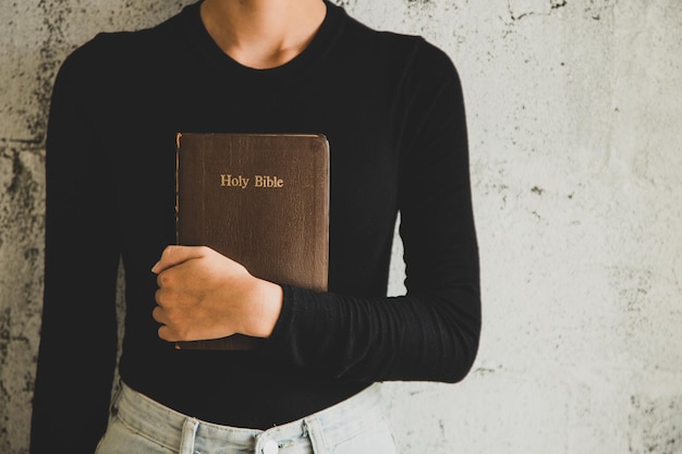 Photo midsection of woman holding bible book against wall