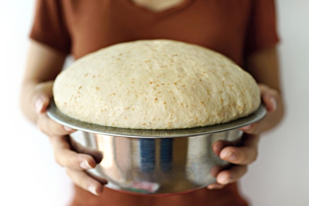 Foto sezione centrale di una donna che tiene la pasta del pane in un contenitore a casa