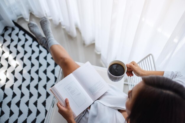 Photo midsection of woman holding coffee cup on bed