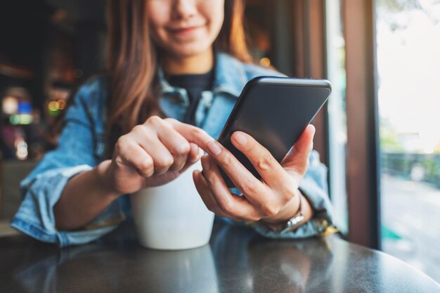 Photo midsection of woman holding coffee cup and mobile phone