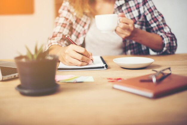 Midsection of woman holding coffee cup on table