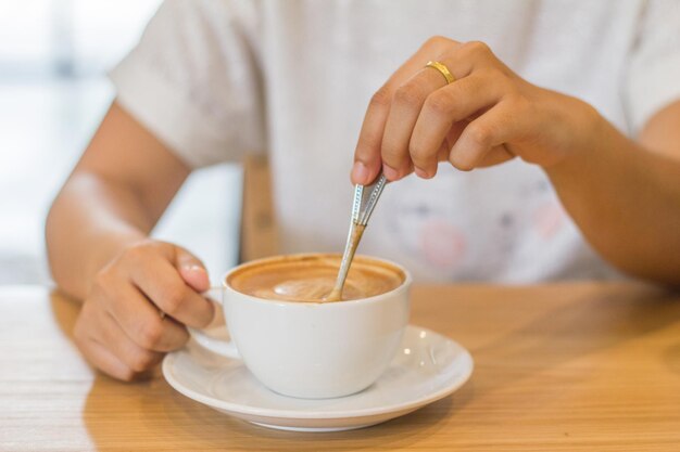 テーブルの上にコーヒーカップを握っている女性のミッドセクション
