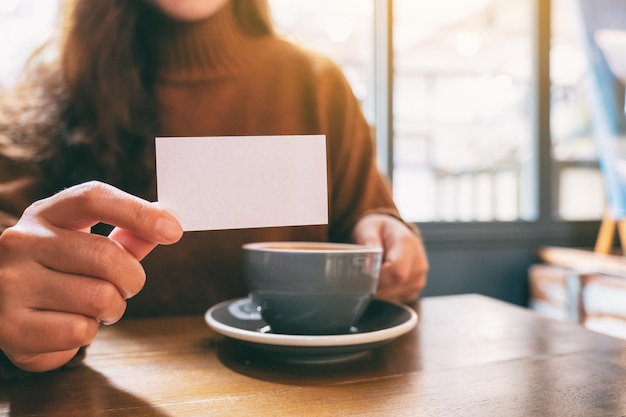 Foto sezione centrale di una donna che tiene una tazza di caffè sul tavolo