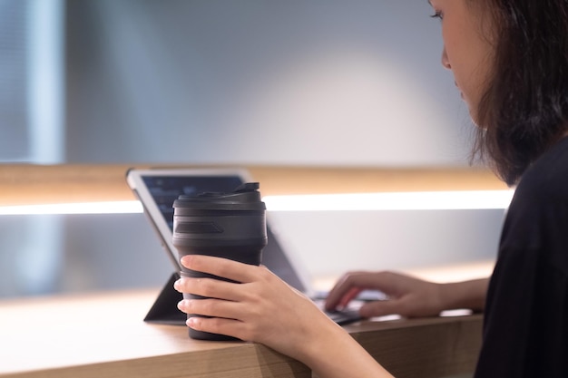 Midsection of woman holding coffee cup on table