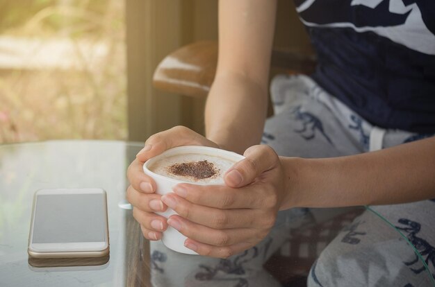 Foto sezione centrale di una donna che tiene in mano una tazza di caffè