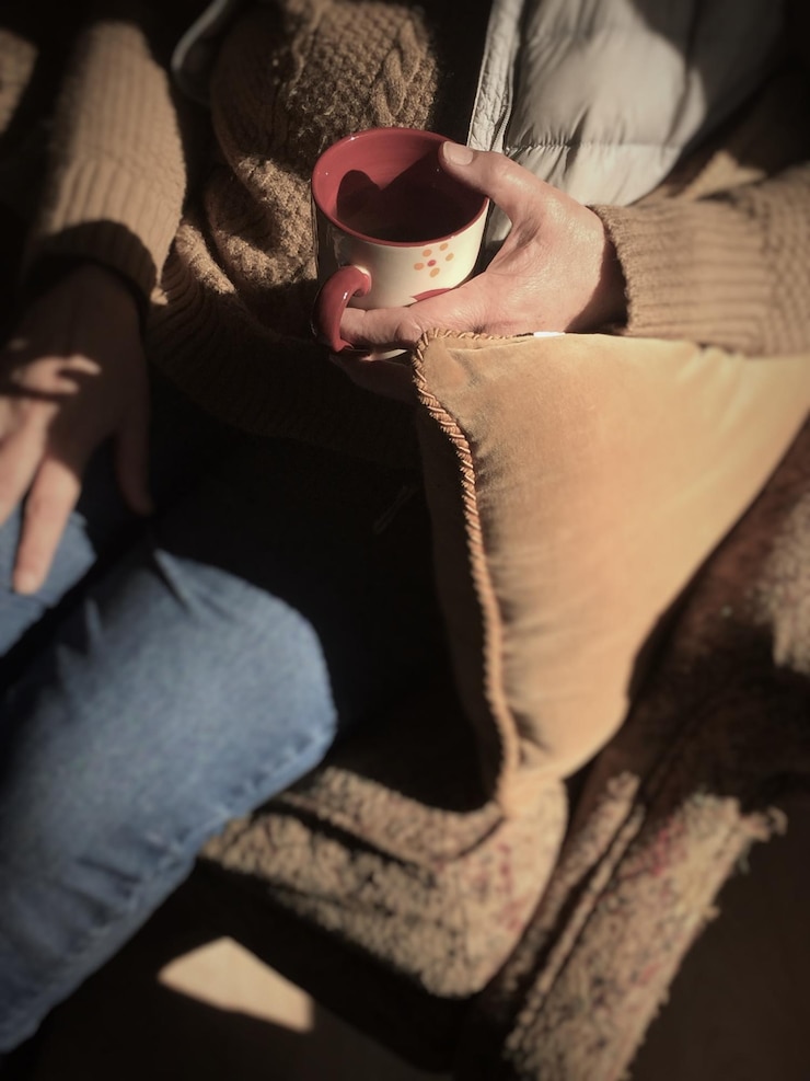 Photo midsection of woman holding coffee mug while sitting on sofa