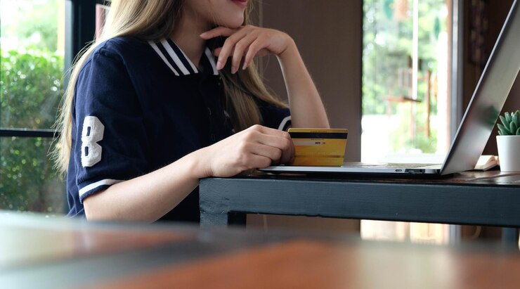 Photo midsection of woman holding credit card and using laptop on table