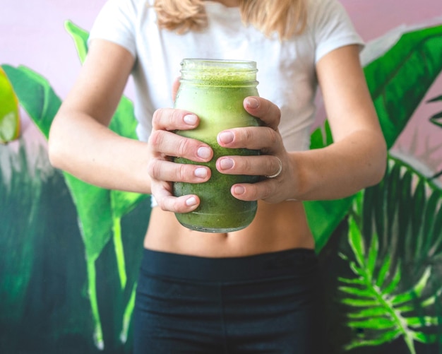 Photo midsection of woman holding drink by houseplant at home