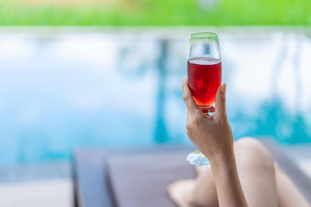 Midsection of woman holding drinking glass at swimming pool