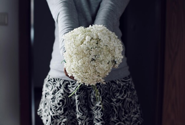 Foto sezione centrale di una donna che tiene un bouquet di fiori