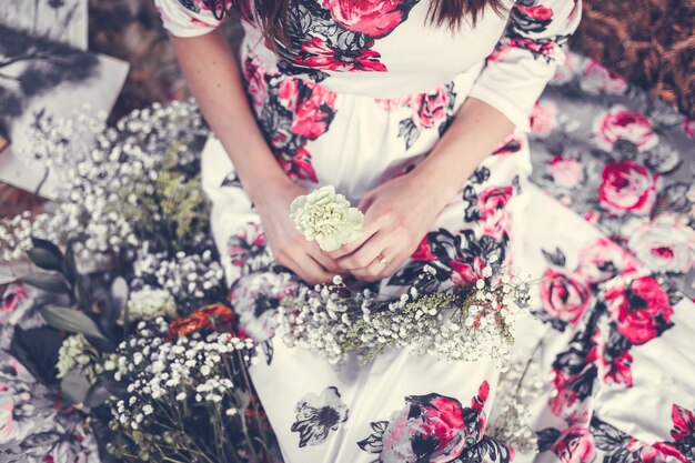 Photo midsection of woman holding flower while sitting outdoors