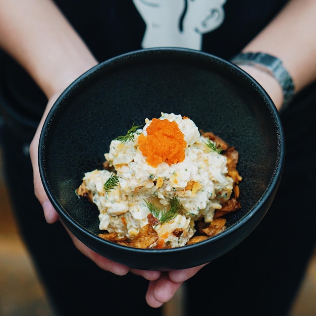 Midsection of woman holding food in bowl at home