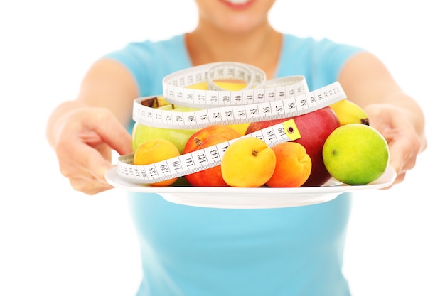 A midsection of a woman holding fruits over white background