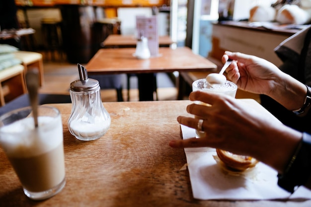 Foto sezione centrale di una donna che tiene un bicchiere di caffè sul tavolo in un ristorante